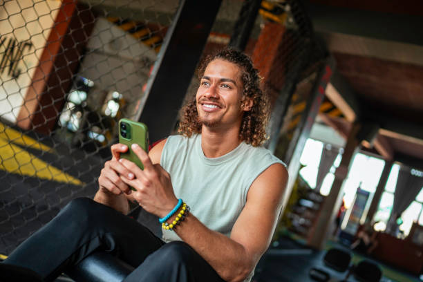 istock Hispanic Male Smiling While Using Smartphone In Gym 2163064859