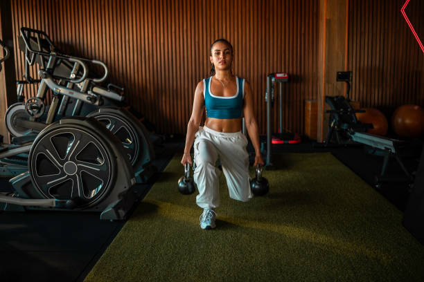 istock Determined Hispanic Woman Lunging With Dumbbells In Gym 2163064886