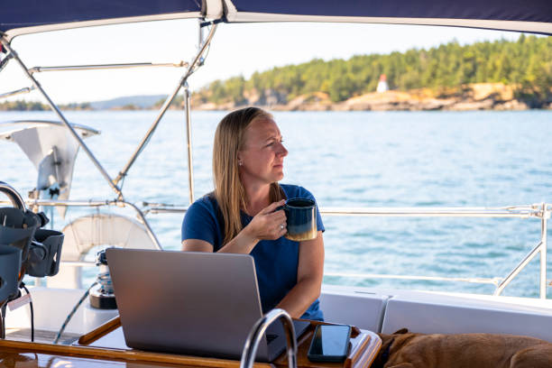 istock Woman works on computer aboard sailboat 2163066713