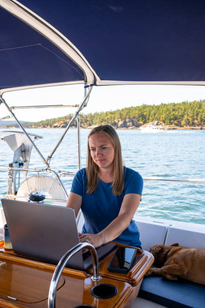 Woman works on computer aboard sailboat