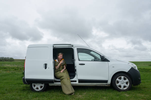 istock young woman sitting in a sleeping bag in a camper van 2163067018