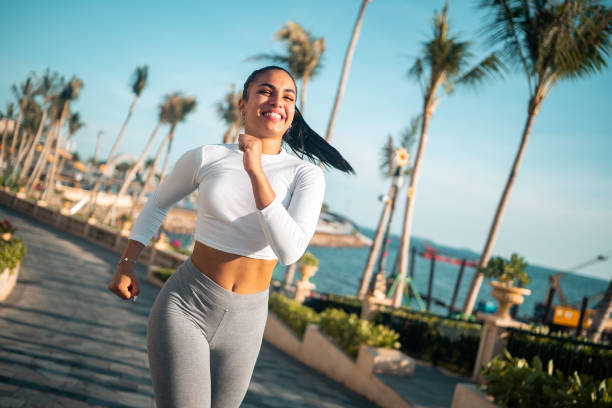 istock Active Hispanic Woman Running Along Coastal Promenade 2163073889