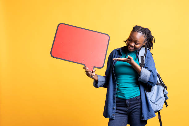 istock Smiling woman holding red speech bubble sign, studio background 2163075512