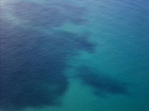 Blue ocean water with dark spot aerial drone view