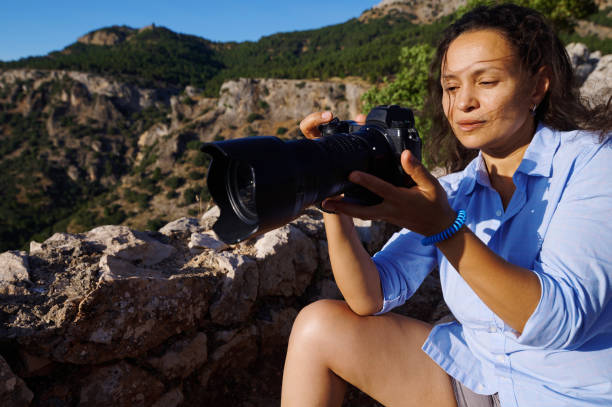 istock Woman photographer adjusting camera settings in mountain landscape on a sunny day 2163080098