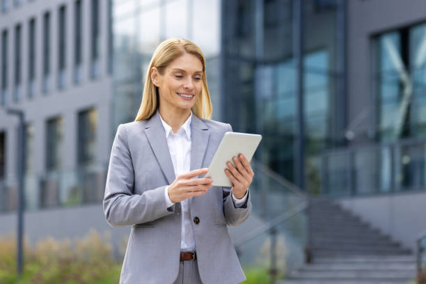 istock Smiling businesswoman using tablet outside corporate office building for work and communication 2163080363