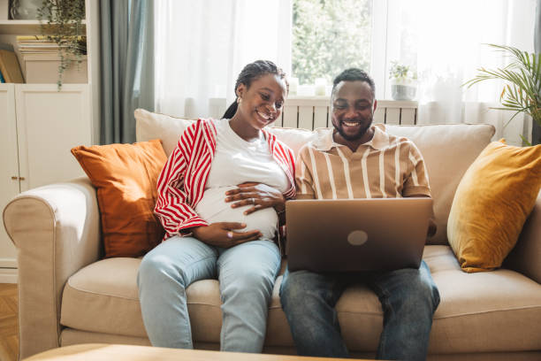 istock Loving pregnant couple using laptop at home 2163084196