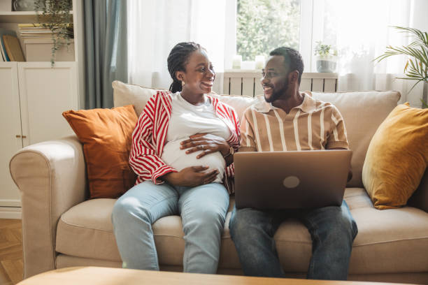 istock Loving pregnant couple using laptop at home 2163084200
