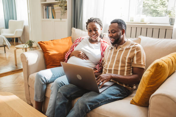 istock Loving pregnant couple using laptop at home 2163084267