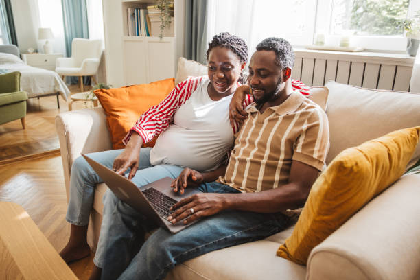istock Loving pregnant couple using laptop at home 2163084269
