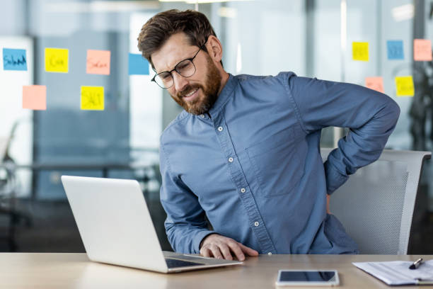 istock Businessman experiencing back pain while working at desk in modern office setting 2163088765