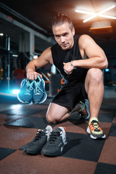 istock young handsome man choosing shoes for run training in gym 2163090090