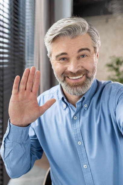 istock Smiling mature office worker greeting on video call with friendly gesture in modern office space 2163093374