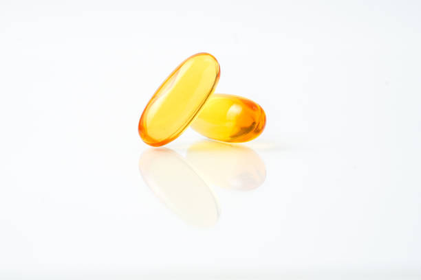 istock Two capsules fish oil,  Softgel Omega 3, Vitamin D,E,A. Supplement capsules isolated white background 2163100511