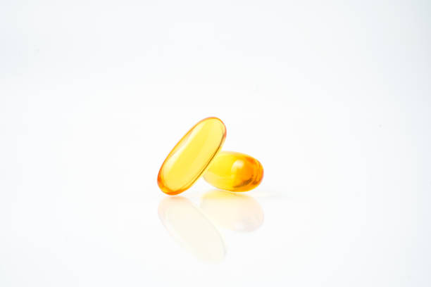 istock Two capsules fish oil,  Softgel Omega 3, Vitamin D,E,A. Supplement capsules isolated white background 2163100531