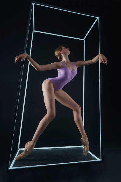 istock allerina in a photo studio on a black background in a light led cube shows ballet elements and stretching 2163114898