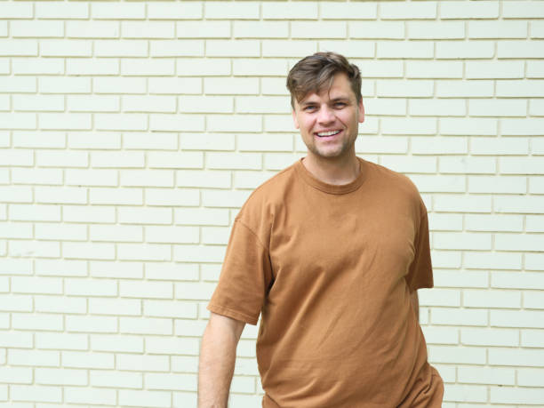 handsome young man in a T-shirt near a brick wall