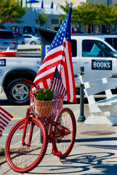 Rehoboth Beach, Delaware, USA - September 17, 2017: A red painted bicycle with an American flag and flowers decorates the sidewalk in front of Browseabout Books, a popular bookstore on Rehoboth Avenue.