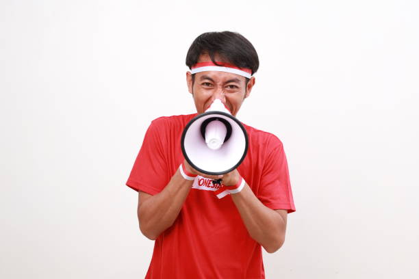 istock Asian man celebrating Indonesia Independence day, shouting using megaphone, looking at the camera. Isolated on white 2163125155