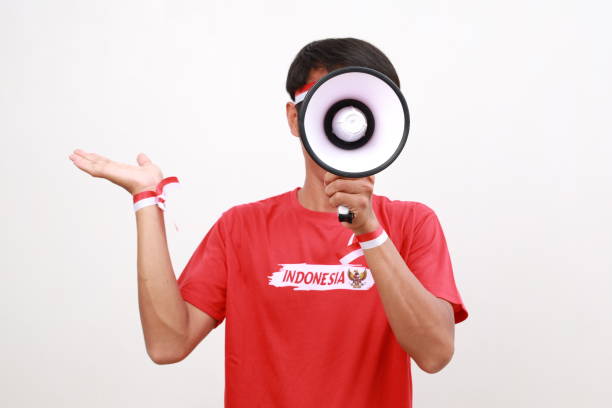 istock Asian man celebrating Indonesia Independence day, shouting using megaphone while presenting sideways. Isolated on white 2163125199