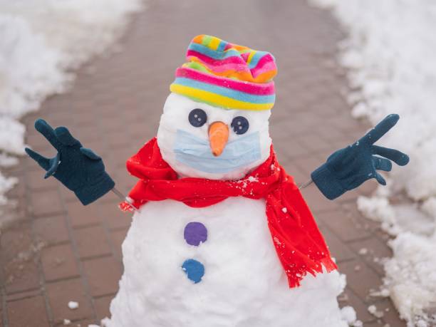 Happy realistic snowman wearing knitted winter scarf and hat looking into the camera, isolated on white background. Christmas holiday or winter vacation and cooling and heating temperatures concept