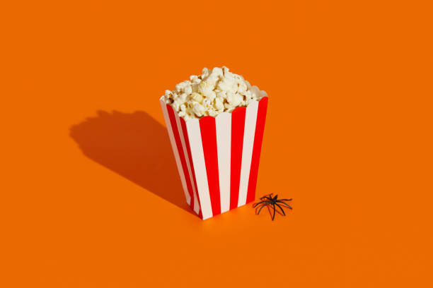 istock Striped box with popcorn and spider on an orange background. Halloween celebration concept. 2163131451
