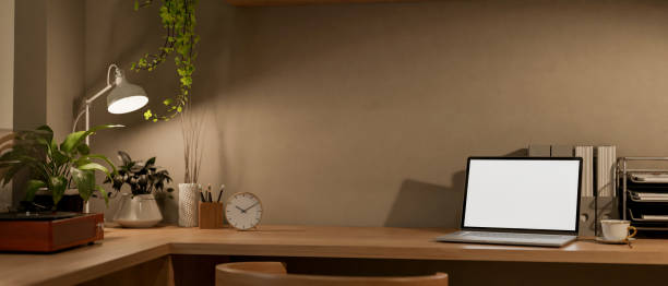istock A laptop computer mockup and illuminated light from a table lamp in a room at night. 2163131858