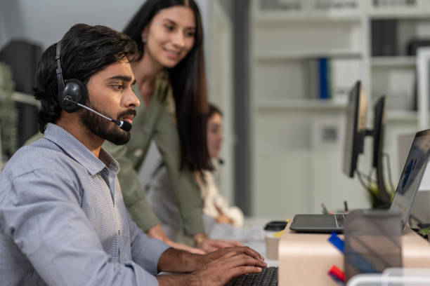 Asian professional businessman using laptop computer video call in office. Attractive handsome professional male employee worker sitting on table working and talking with customer at night in company.