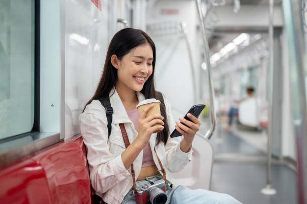 istock A happy Asian female tourist is using her phone, reading text messages while taking a sky train. 2163134477