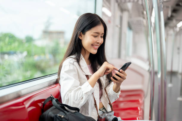 istock A beautiful, happy Asian female passenger is using her smartphone while sitting in a sky train. 2163134638