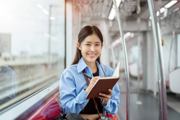 istock A positive Asian female tourist is writing in her diary while commuting by sky train. 2163135309