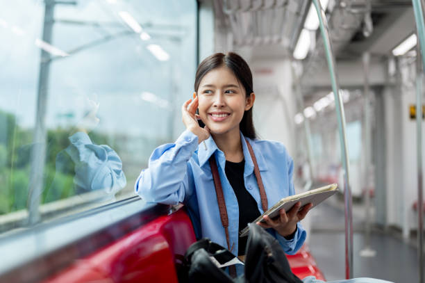 istock A female passenger is looking at the view outside while using her digital tablet on a sky train. 2163135387