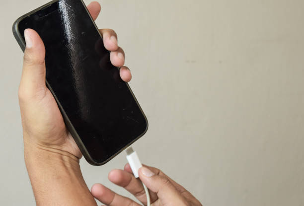 istock Mobile smart phones charging. Man hands plugging a charger in a smartphone 2163135751