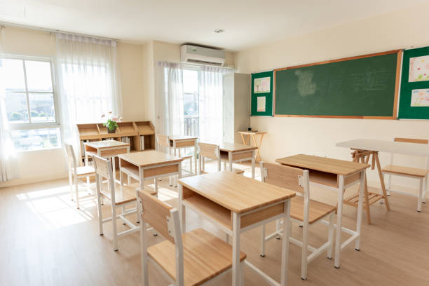 istock Shot of empty classroom with chairs under desks in elementary. School during vacation or holidays, A teaching classroom without students during a term break or the end of semester in kindergarten. 2163141048