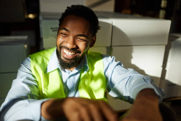 Happy African American inspector day dreaming while resting on a break in a storage room.