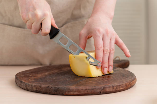 istock A woman cuts cheese into thin slices. 2163144041