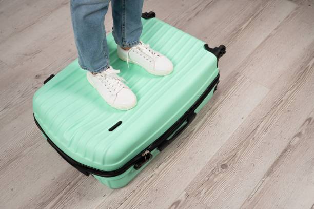 istock Woman standing with her feet on a suitcase. 2163146306