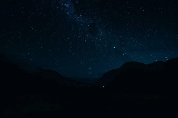 A mesmerizing view of a starry night sky with a glowing tent set up in the wilderness. The scene captures the peacefulness and beauty of camping under the stars, perfect for adventurers and stargazers.