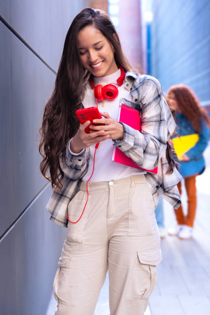 istock Young latin woman browsing the internet using mobile device outdoors.Vertical 2163151901