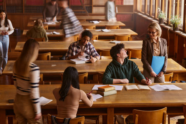 istock Happy senior professor talking to male student on a class in library. 2163155446