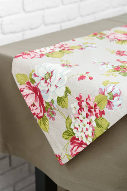 istock Floral Table Runner on a Beige Tablecloth Against a White Brick Wall 2163156330