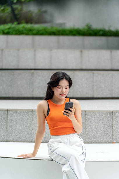 istock Young Asian Woman Using Her Phone In a Park Relaxingly 2163161988