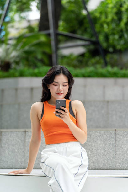 istock Young Asian Woman Using Her Phone In a Park Relaxingly 2163162002