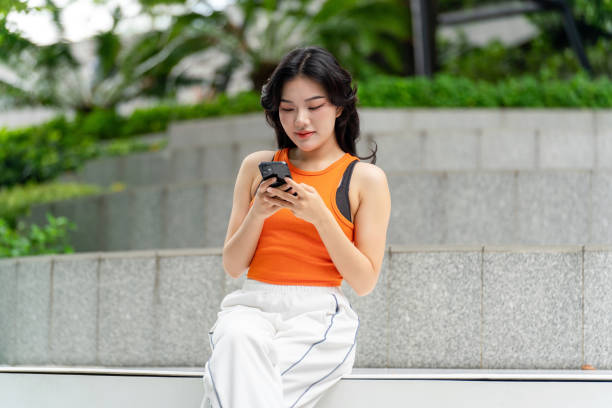 istock Young Asian Woman Using Her Phone In a Park Relaxingly 2163162089