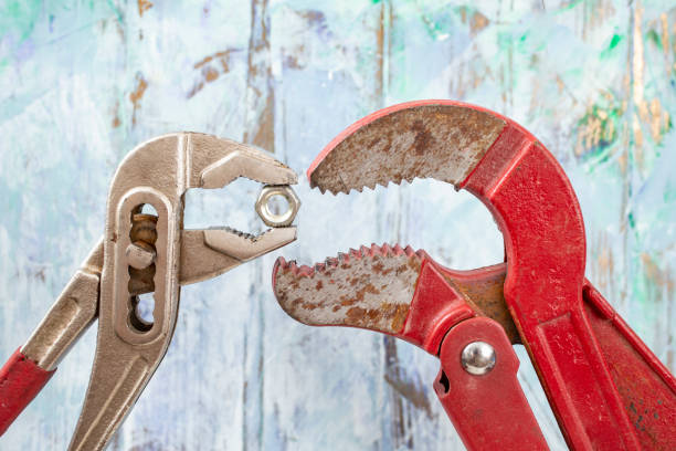 Two adjustable wrenches feeding each other one bolt on blue defocused stucco wall. Hungry opened mouths metaphor