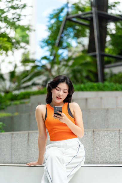 istock Young Asian Woman Using Her Phone In a Park Relaxingly 2163162192