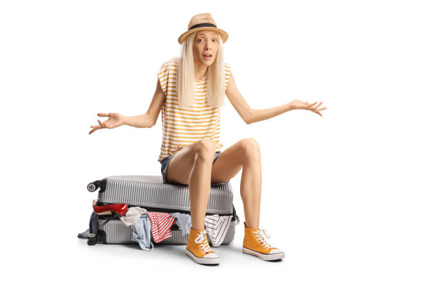 istock Confused young woman sitting on an overpacked suitcase 2163162522