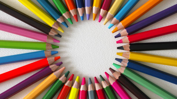 Vibrant multi-colored color pencils or crayons in a circle, on a textured white, watercolor paper background. The pencils are arranged pointing to the circle-shaped blank center. Good copy space in the center. Shot from directly above. Concept relating to diversity, variation, multiculturalism, teamwork and unity etc.