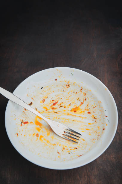 istock Dirty empty plate and fork. Messy dish on wood table 2163165077