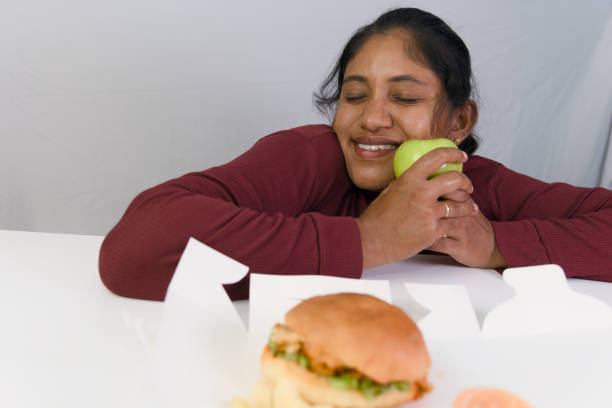 istock Woman deciding between a green apple and burger 2163168974
